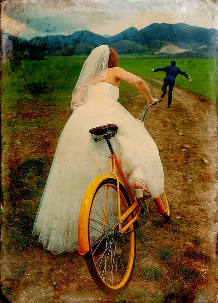 Sposa su arancione bici retrò sta inseguendo dopo uno sposo in abito da sposa blu con una bottiglia di birra. concetto di matrimonio. Variante retrò . — Foto Stock