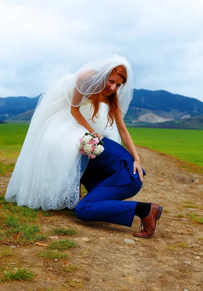 Bräutigam lugt unter Brautkleid - lustiges Hochzeitskonzept. — Stockfoto