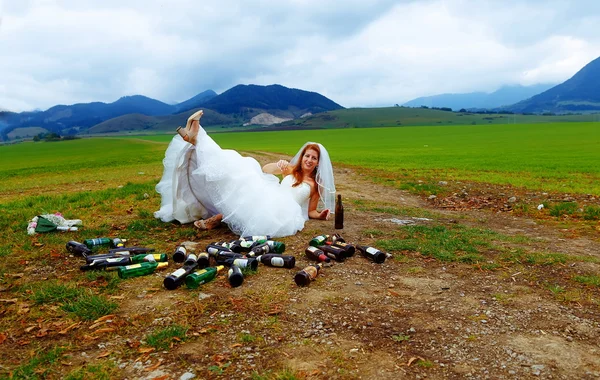 Mariée ivre avec beaucoup de bouteilles de bière vides dans le paysage de montagne concept de mariage drôle . — Photo