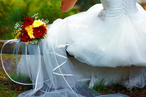 Detalhe de um vestido de noiva com um buquê de casamento fora . — Fotografia de Stock