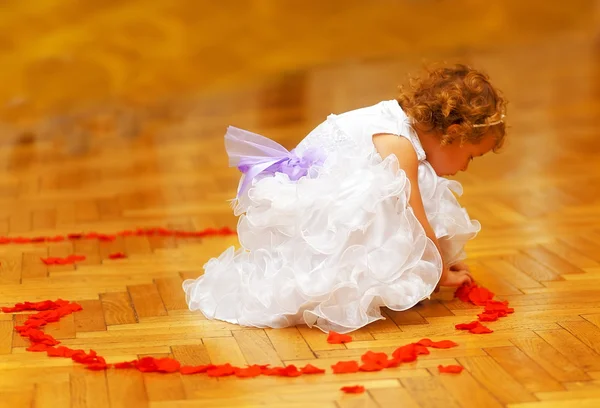 Little bridesmaid girl in white dress forming a heart shape out of rose petals.  wedding concept. Stock Photo