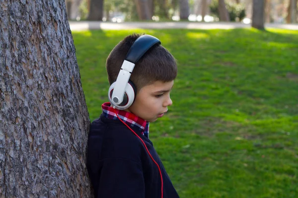 Garçon dans un arbre écoutant de la musique — Photo