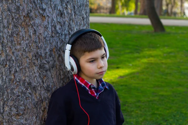 Niño en un árbol escuchando música — Foto de Stock