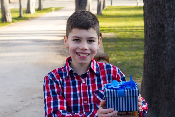 Pojke i rutig skjorta innehar en gåva — Stockfoto