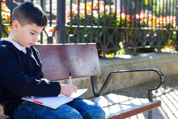 Boy escribe en cuaderno — Foto de Stock