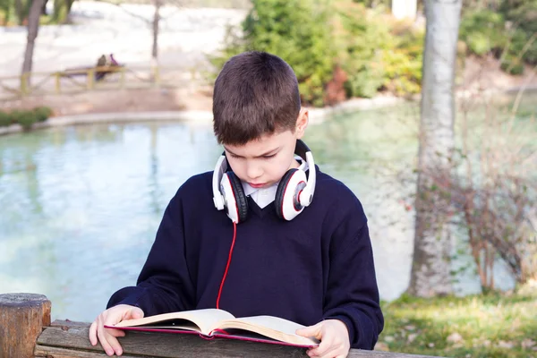 Chłopiec czyta książkę w parku — Zdjęcie stockowe