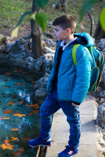Fiú a kék kabát a táskáját a parkban — Stock Fotó