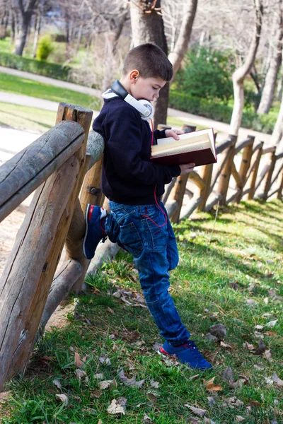 Garçon dans le parc lisant un livre — Photo