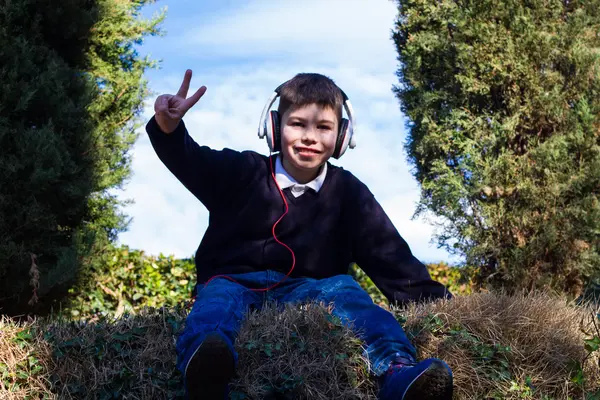 ヘッドフォンで公園で陽気な少年 — ストック写真