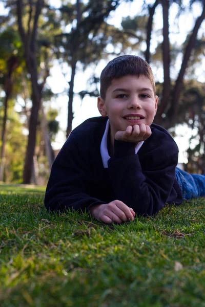 Chlapec se sluchátky ležící na trávě a usmívá se — Stock fotografie