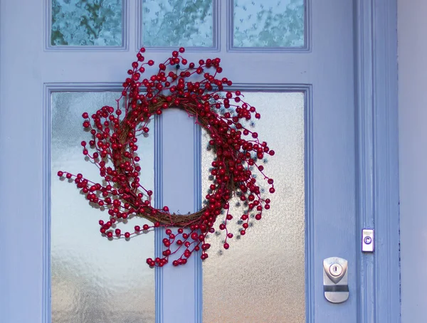 Yakın plan: Kırmızı Doğal Meyveler Noel Çelengi Dekorasyonu Evin Ön Kapısı 'nda. İngiliz ev tarzı. Noel ve Yeni Yıl Geleneksel Dekorasyonu Ev Dışı. Dikey Görüntü.