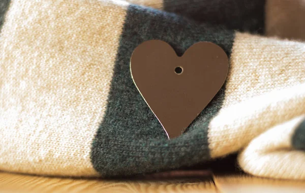 Aşkın Romantik Sembolü ve Sevgililer Günü Kavramı. Yakın plan: gümüş kalp süslemesi güzel, sıcak çizgili bir eşarpta.. 