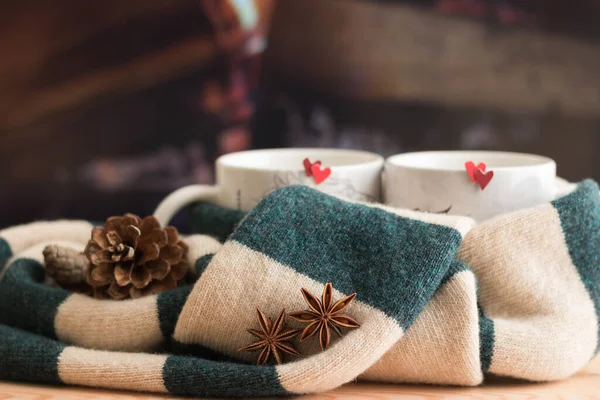 Love Moood ve birlikte sıcak kalın - romantik yaratıcı natürmort yaşam kompozisyonu. Yakın plan Yeşil Atkı Kırmızı Kalpler ile İki Kupa Bağladı. Baharatlı içecek. Arka plan şöminede odun gibidir.. 