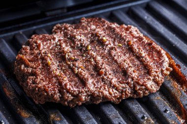 Yağları azaltmak için elektrikli ızgarada ızgara burger köftesi ve ızgara et veya sığır eti. Küçük biber taneleriyle sıcak köfteye bakıyorum.