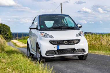 Düellocular, Almanya - 06 28 2020: Çevre dostu üçüncü nesil manzara sahnesinde bir köy yolunda akıllı 451 ED elektrikli araba