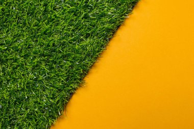 Sarı üniforma arkaplanındaki yapay çimlerin üst görünümü, plastik grafikler tarafından çapraz kesilir, şablon ya da arkaplan olarak kullanılır