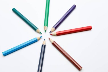 Yıldız şekli oluşturan renk kalemlerinin üst görünümü, beyaz üniforma arkaplanındaki bir yeri gösteren kalem uçları, okul konuları etrafında bir Powerpoint şablonu veya kompozisyon için kullanın