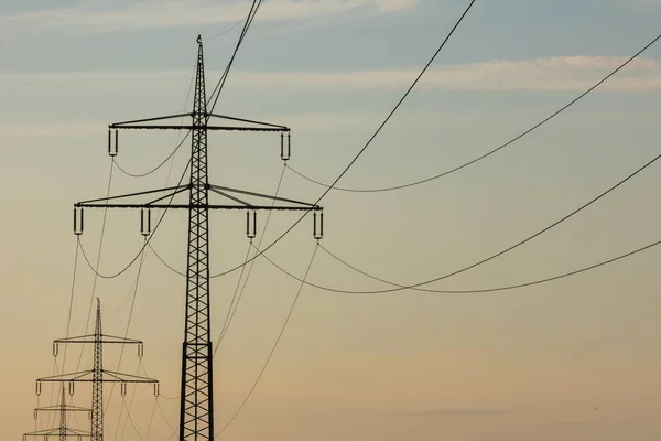 Gün batımında elektrik kabloları olan elektrik direkleri, sarıdan maviye ışık eğimi, elektrik hatları ufukta beliriyor, elektrik hatları günlük yaşamımızda çok önemli.