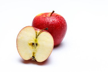 iki kırmızı elma su sıçratır beyaz üniforma arka planda, bir elma ikiye bölünür meyve sapına ve tohumlara bakarak.