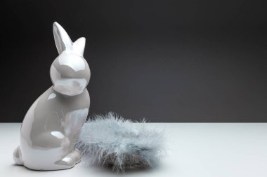 Beyaz paskalya tavşanı krem beyaz paskalya tavşanı yakıtının yanında siyah üniformalı arka plandaki tüylerle dolu bir paskalya yuvası, metin alanı, paskalya süslemesi ya da tebrik kartı şablonu