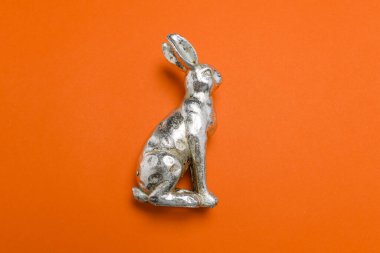 Paskalya arkaplanı olarak Paskalya sanal buluşması arka planı olarak kullanılan kırmızı üniformalı, yumuşak gölgeli, gümüş metalik paskalya tavşanı figürünün yan görüntüsü.