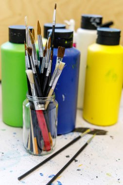 Bir sanat stüdyosunun ya da sanatçıların yakın plan çekimlerinde, resim cam bardakta akrilik renkli boya fırçalarını gösteriyor.