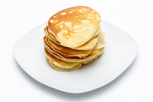 High angle view of a stack of pancakes on a white plate on white uniform background, typical American breakfast food