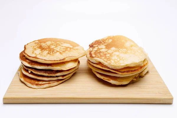 Twee Stapels Zelfgemaakte Pannenkoeken Een Bamboe Snijplank Witte Uniforme Achtergrond — Stockfoto