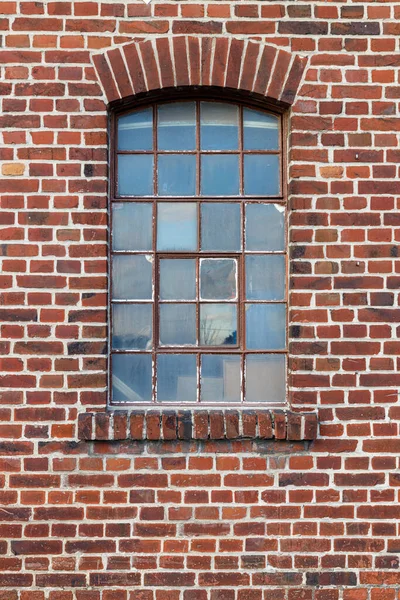 Old damaged window in a rusty frame on a industrial red brick wall, use as game asset reference or texture