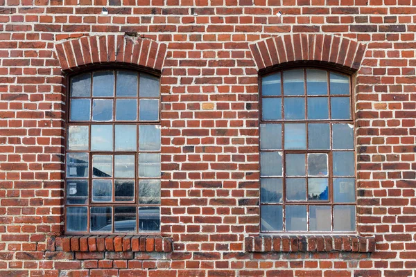 Two industrial looking windows with broken pieces of glas, the window frame is rusted, the brick wall is weathered with many imperfections. Use as game asset texture reference.