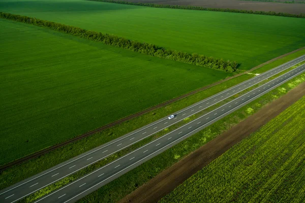 Biały Samochód Jadący Asfaltową Drogą Wzdłuż Zielonych Pól Widziany Powietrza — Zdjęcie stockowe