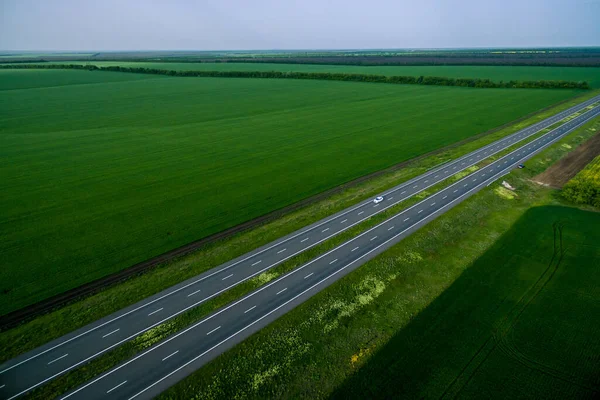 Biały Samochód Jadący Asfaltową Drogą Wzdłuż Zielonych Pól Widziany Powietrza — Zdjęcie stockowe