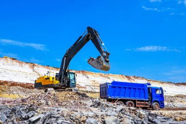 Kil madenciliği. Kazıcı kil çıkarıp mavi kamyona yükler. 