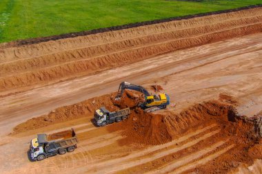 Aşırı yük işe yarıyor. Kil madenciliği. Kazıcı kil çıkarmak için toprağı parçalar ve gri kamyona yükler. Drone fotoğrafı. hava görünümü