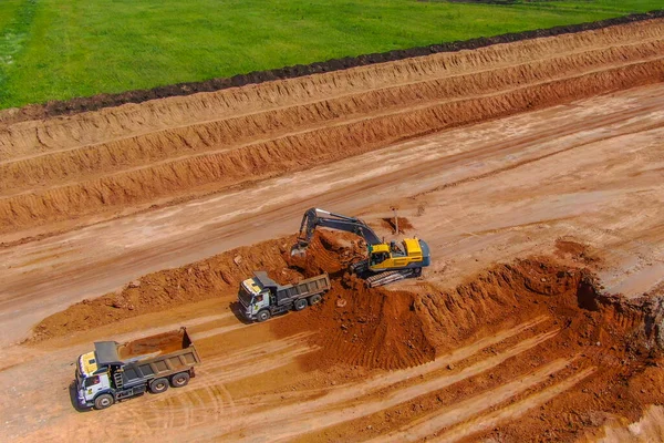 Aşırı yük işe yarıyor. Kil madenciliği. Kazıcı kil çıkarmak için toprağı parçalar ve gri kamyona yükler. Drone fotoğrafı. hava görünümü