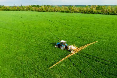 İlkbahar insansız hava aracı yüksek açı görüşünde yeşil alanda traktör spreyi gübresi, tarım arka plan kavramı.