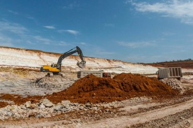 Sarı kazıcı kilden gri kamyona yükleniyor. Çamur madenciliği. 