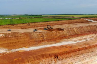 Aşırı yük işe yarıyor. Çamur madenciliği. Kazıcı toprağı parçalayarak kil çıkarıyor ve gri kamyona yüklüyor. İHA fotoğrafı. hava görünümü