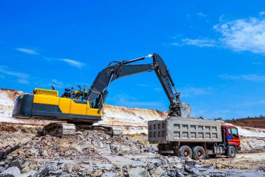 Taş ocağı. Sarı buldozer mayınları gri kamyona yükleniyor. Çamur madenciliği. 