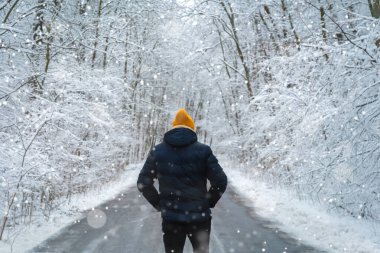 Adam kış ormanlarında yolda yürüyor. arka plan