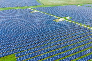 Temiz enerji üretimi için kullanılan yeşil çimlerin üzerindeki güneş parkı. Hava manzaralı. Drone fotoğrafı