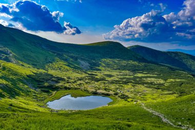 Yazın dağ gölü olan güzel bir manzara. Göl kenarında turist çadırları var.
