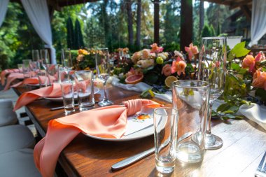 Açık hava partisi için düğün hazırlıkları masası servis edildi. Taze çiçekler ve meyvelerle süslenmiş. Dekorasyon ayrıntıları. Dışarıdaki restoranda servis edilen masanın detaylarını kapat.. 