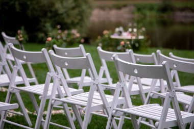 Tören için düğün sandalyeleri. Açık havada yapılacak bir düğün için şık bir dekorasyon. Güzel beyaz mobilyalarla açık havada düğün..  