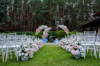 Ormandaki güzel düğün dekoru. Açık havada yapılacak bir düğün için şık bir dekorasyon. Güzel beyaz mobilyaları olan açık hava düğün töreni. Tahta misafir sandalyeleri..
