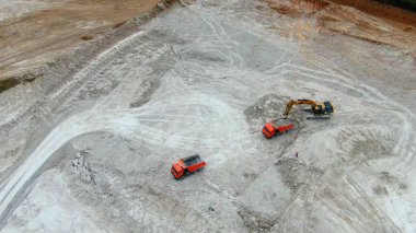 Sarı kazıcı kil çıkarır ve kırmızı kamyonlara yükler. İHA görüntüsü. mavi killi panorama ocağı. 