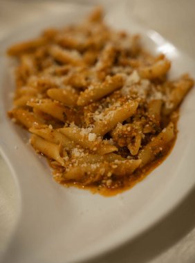 İtalya 'da baharatlı domates soslu makarna ve beyaz tabakta beyaz bir yaprak şeklinde peynir (seçici odaklanma))