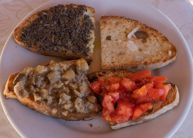 İtalya 'da porcini mantarlı bruschetta, domates, trüf, yuvarlak beyaz tabakta (seçici odak))
