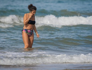 Bufalara, İtalya - Eylül 02, 2020, kumsalda elinde telefonla dolaşan kadın. İtalya 'da ikinci koronavirüs dalgası (covid19)