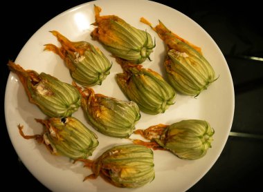 Koyu arkaplanda beyaz bir tabakta doldurulmuş kabak çiçekleri resmi, geleneksel İtalyan yemekleri (seçici odak))